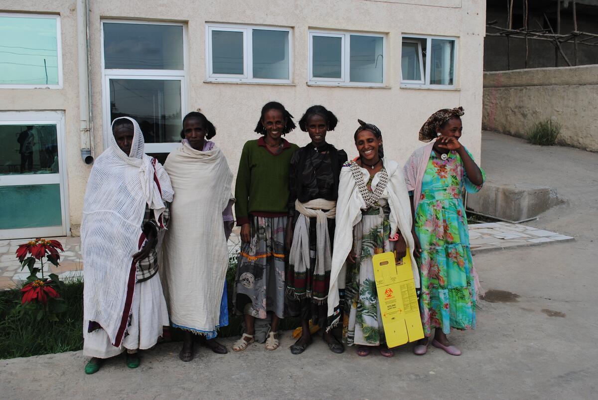 Women standing in a group wearing local garb, smiling for the camera
