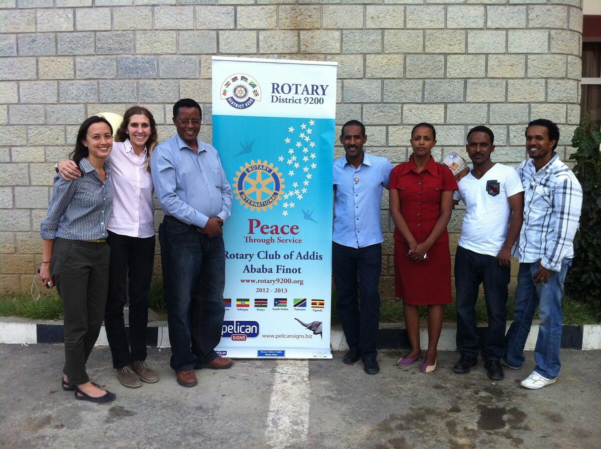 group of people standing around standing banner advertising Ethiopian rotary club event 