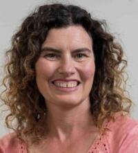 a smiling woman professor with short dark curly hair