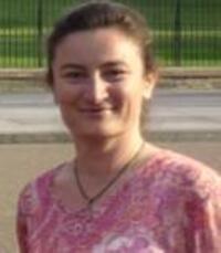 a smiling woman scholar wearing pink t-shirt